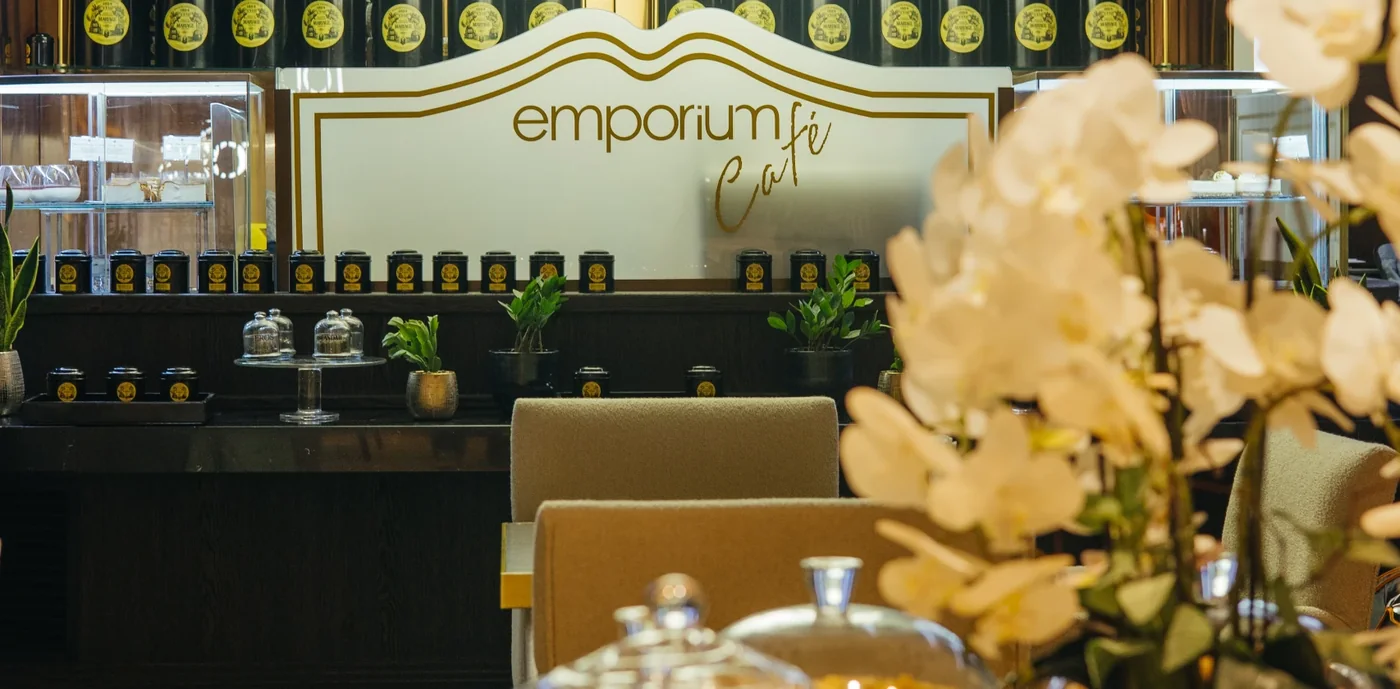Emporium Café в Port Baku: стойка с жестяными банками чая и фирменной надписью emporium café