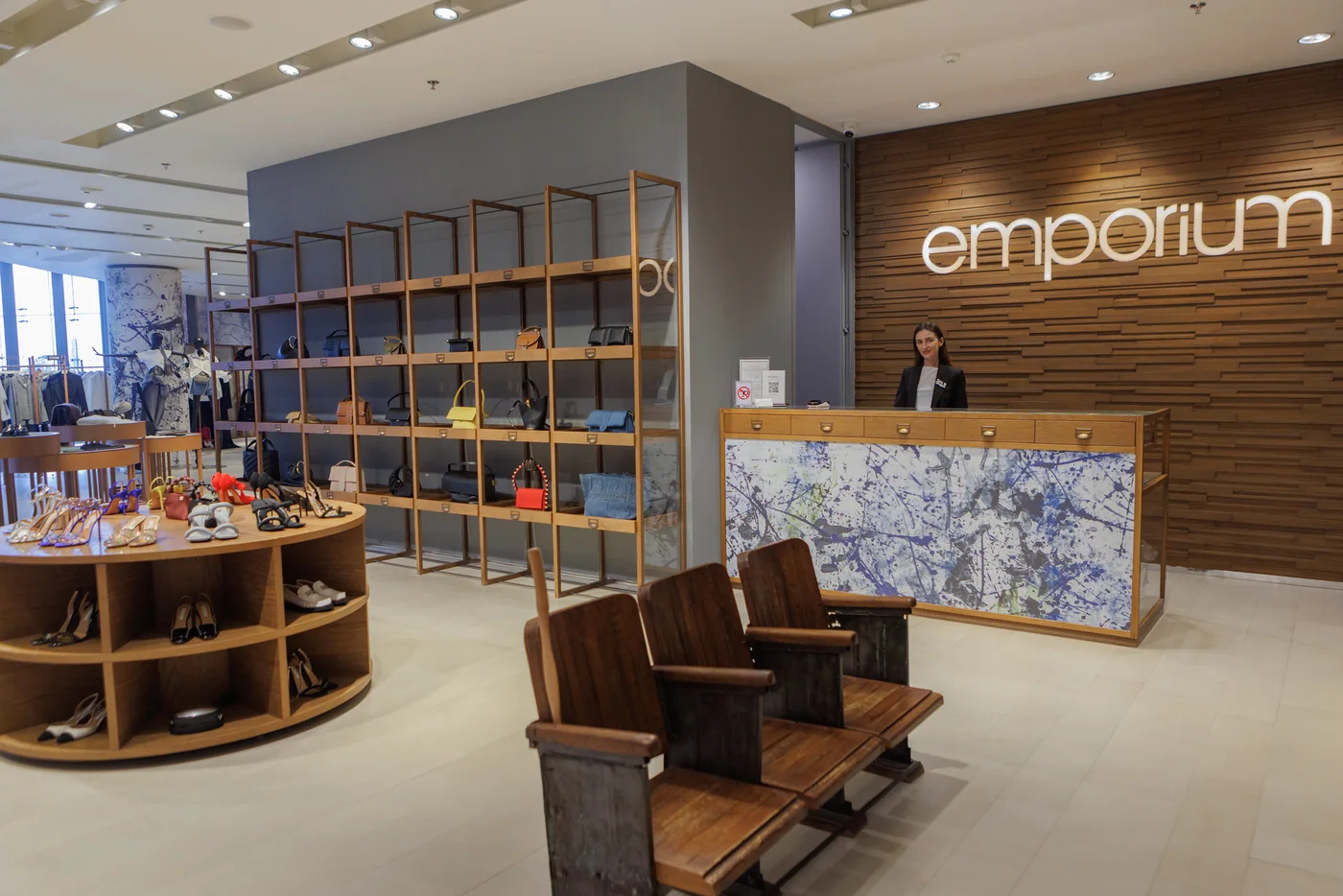 Отдел Emporium Young: стойка администратора у деревянной стены с логотипом, полки с сумками и обувью